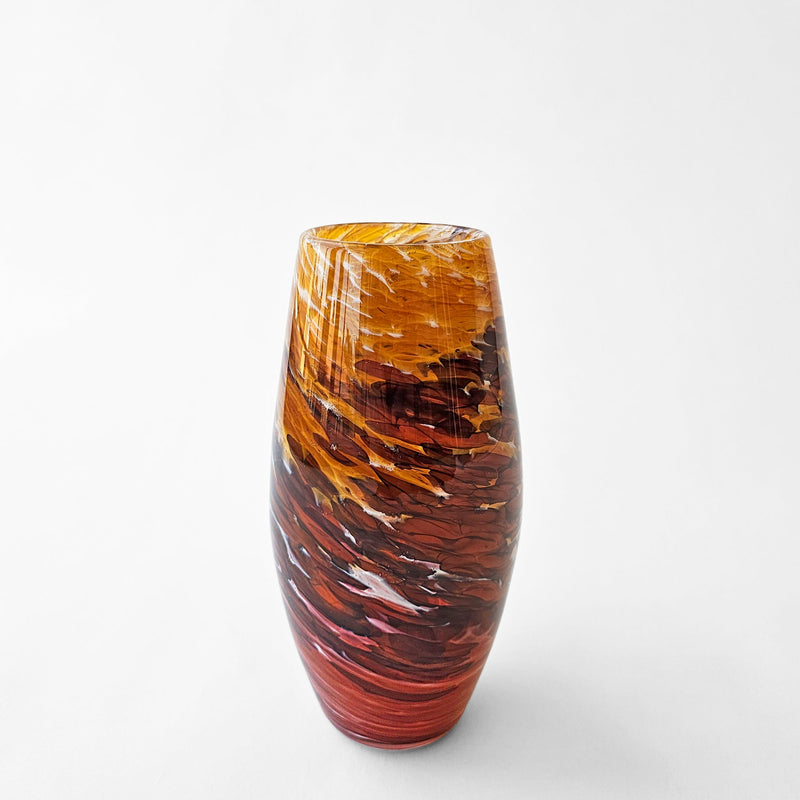 Orange red glass vase with swirl design.