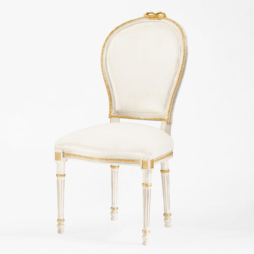 White chair with gold trim and cream fabric.