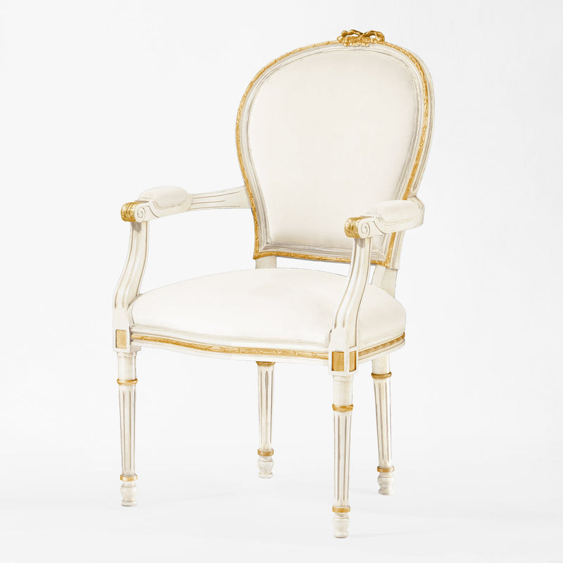 White armchair with gold trim and cream fabric.